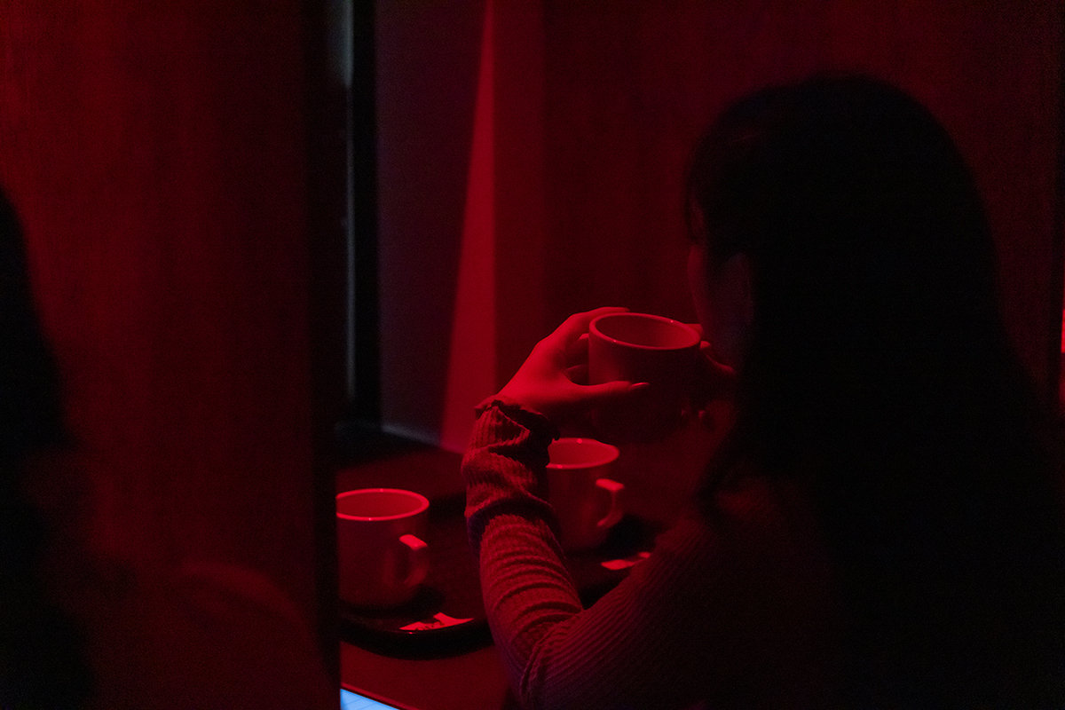 Someone sips coffee in a red lit room