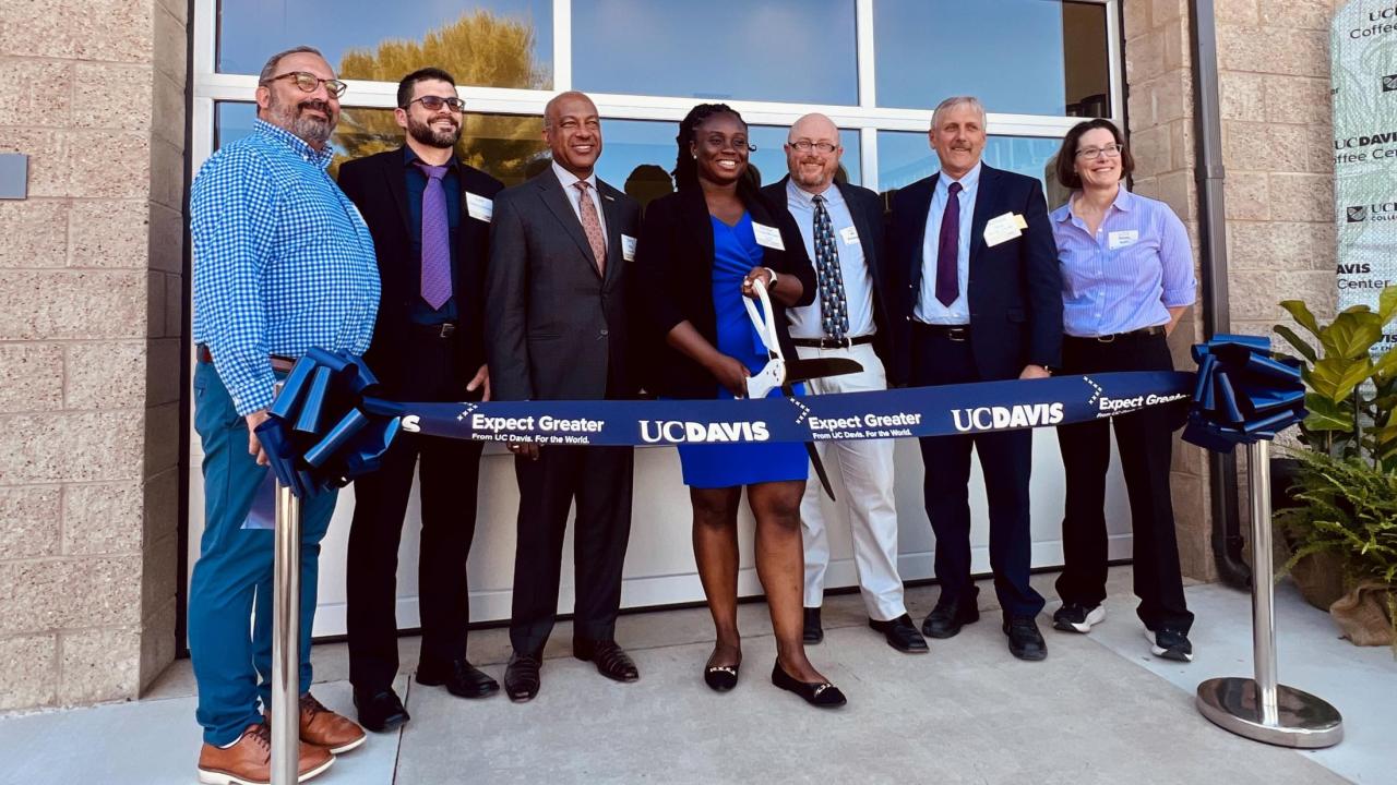 Seven people stand in front of the coffee center at a ribbon cutting ceremony