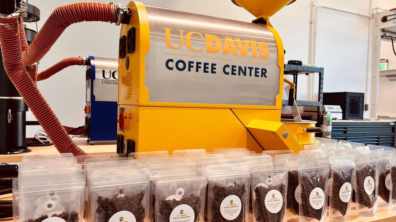 Many bags of coffee beans in front of a large yellow Coffee Center machine