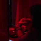 Someone sips coffee in a red lit room