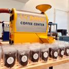 Many bags of coffee beans in front of a large yellow Coffee Center machine